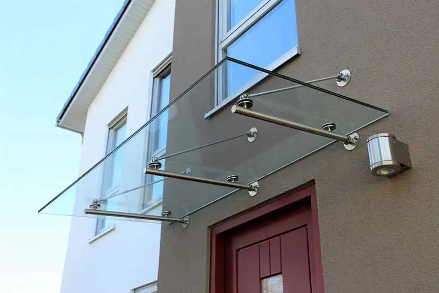 Frameless glass canopy on stainless steel rods above an entry door