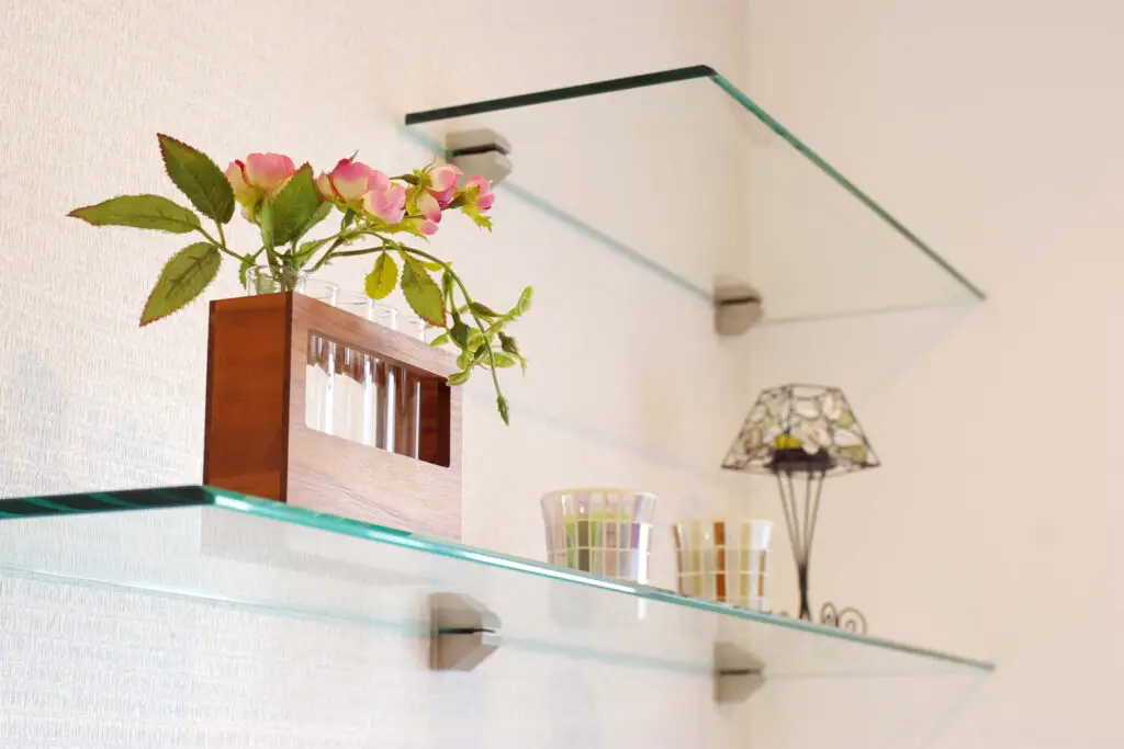 Floating glass shelves on metal brackets holding flowers and decor