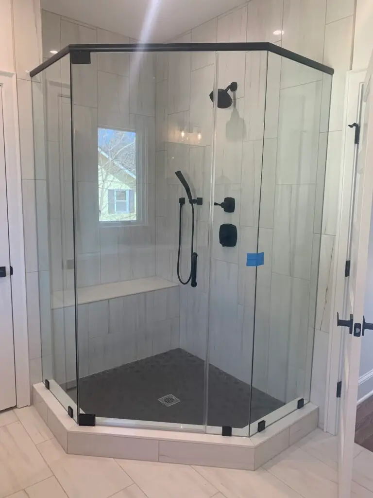 Frameless neo-angle shower enclosure with matte black hardware and a tiled shower pan
