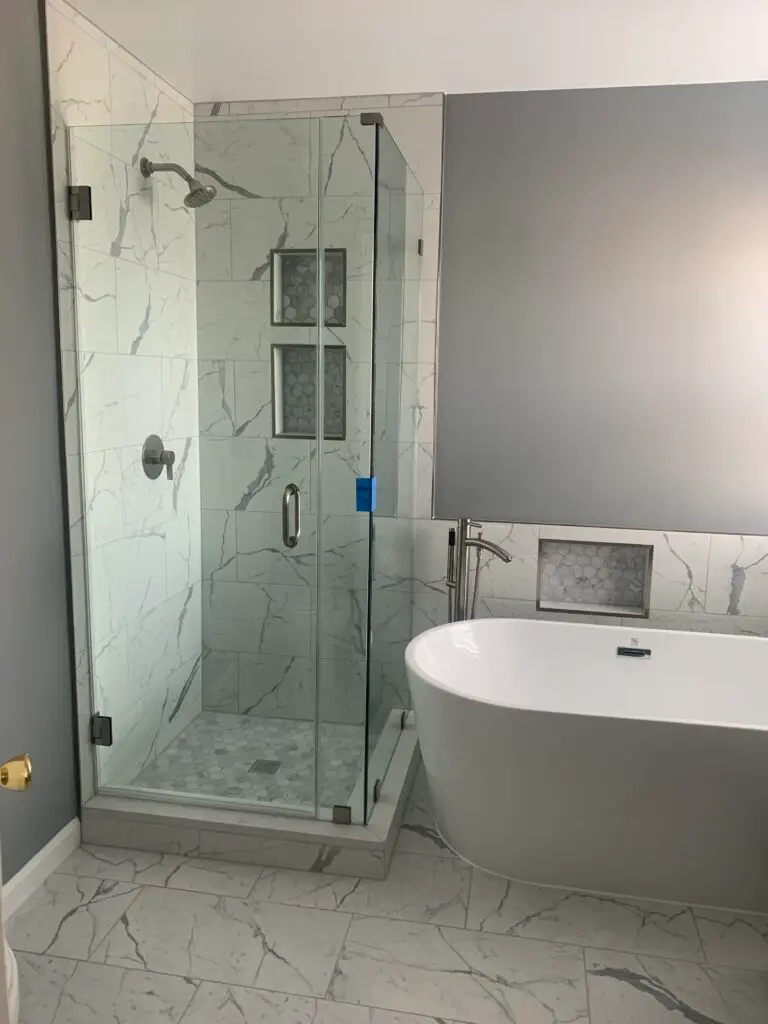 Frameless neo-angle shower enclosure in marble tile with matte black hardware