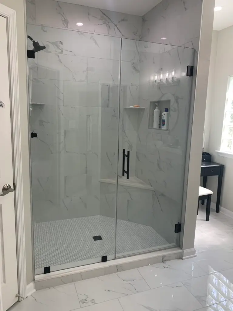 Frameless shower door and return panel with matte black hardware and a tiled bench