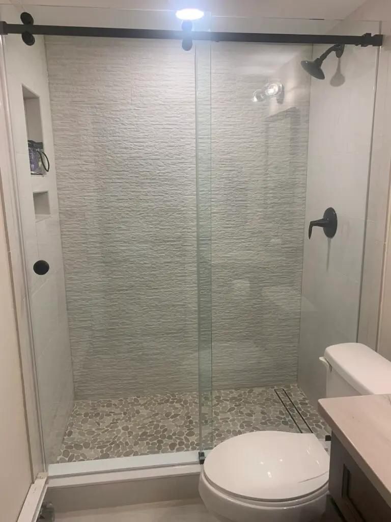 Sliding bypass shower doors with brushed hardware over a tiled shower base