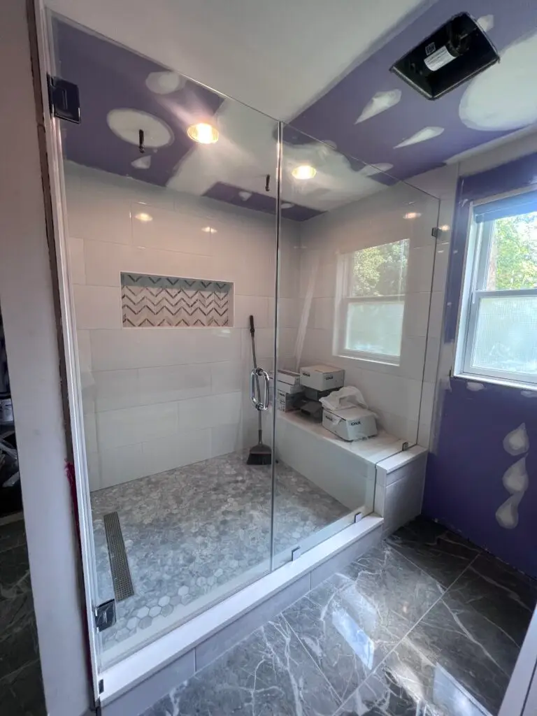 Frameless shower enclosure with a tiled bench and rain shower head