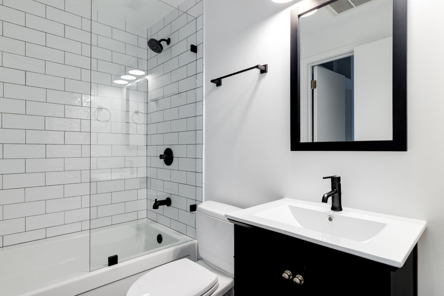 A bathroom with a black cabinet and subway tiles.