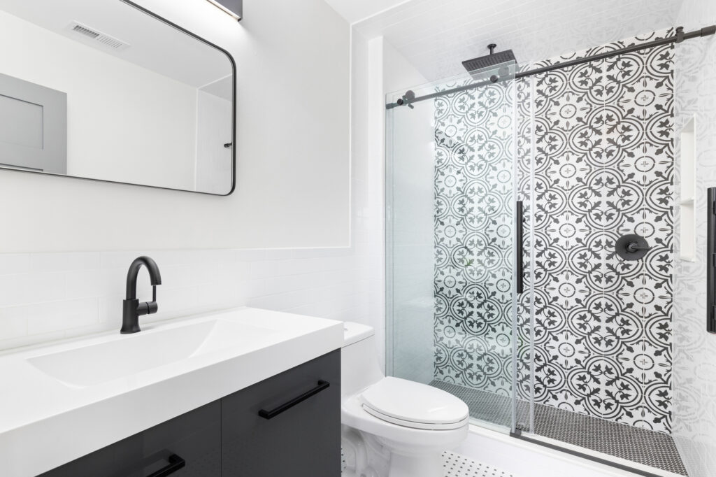 A bathroom with a grey cabinet and tiled shower.