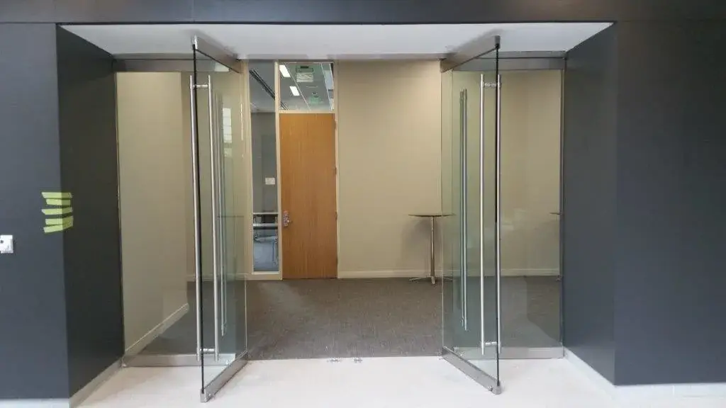 All glass double entrance doors with stainless ladder pulls into an office suite