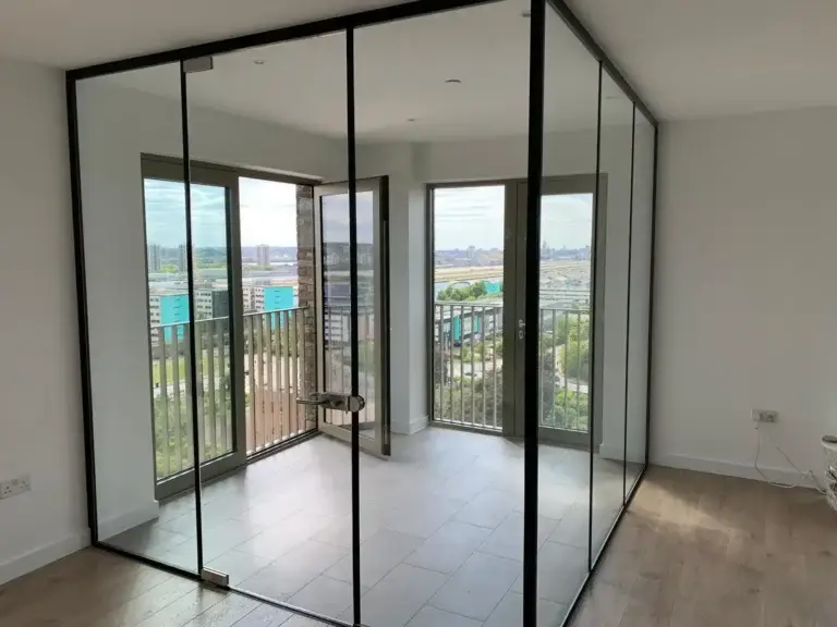 Black-framed glass corner partition with a door in a bright room