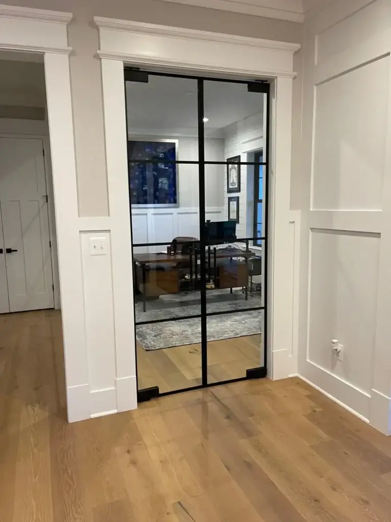 Black grid glass double doors opening into a home office