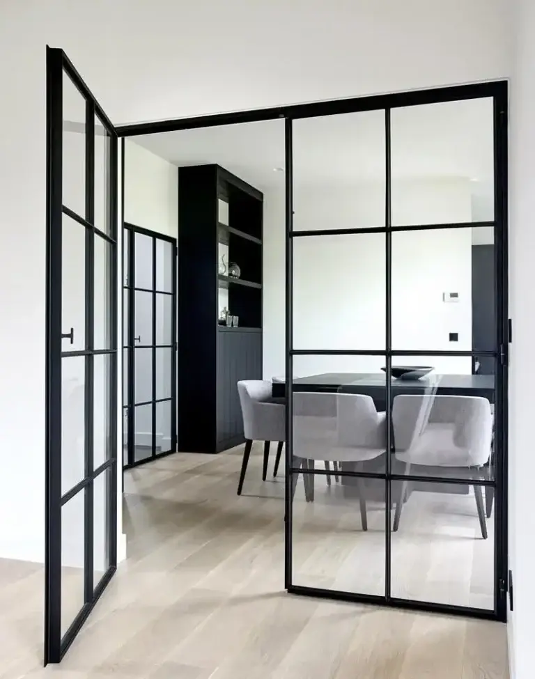 Black grid glass partition with a door beside a dining area