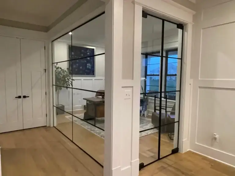 Black grid glass wall and double doors enclosing a home office