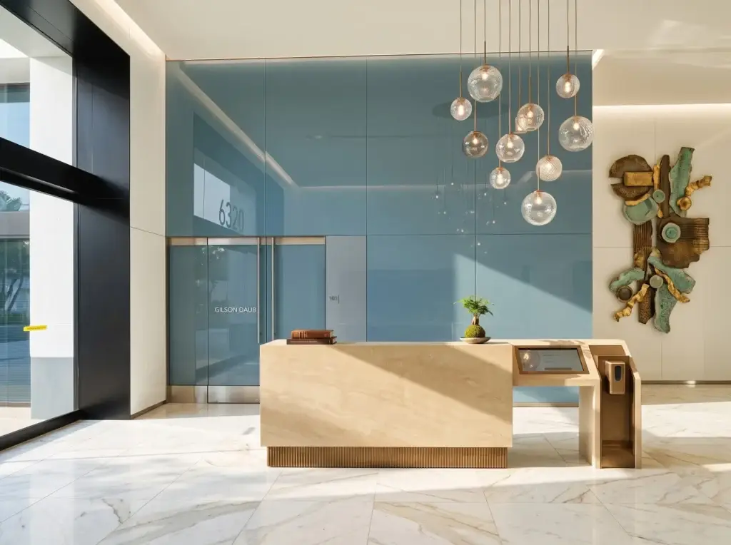 Blue back-painted glass wall behind a stone reception desk in an office building lobby