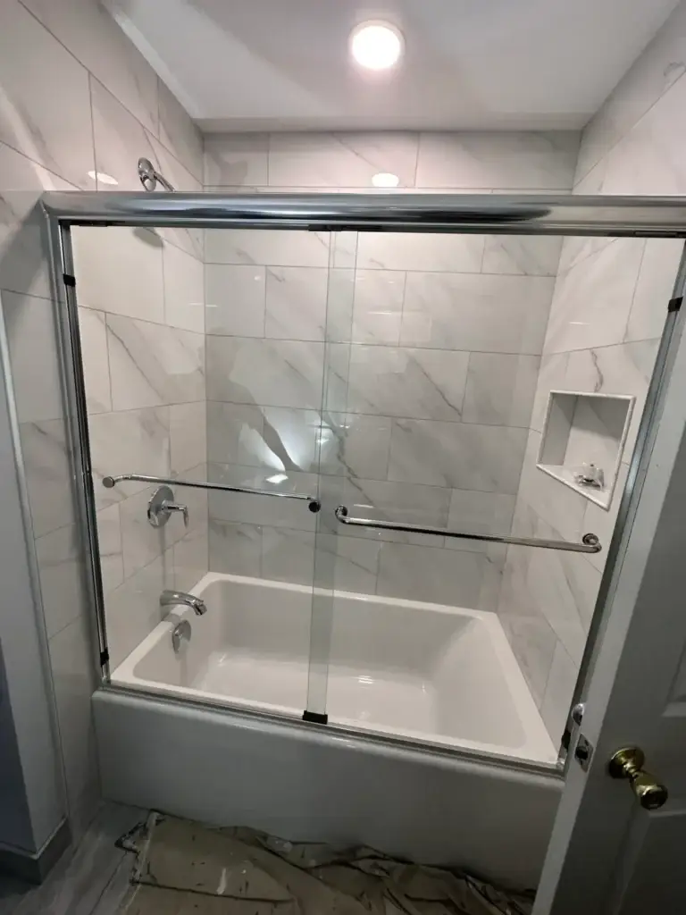 Bypass sliding glass tub doors with towel bars and marble-look tile