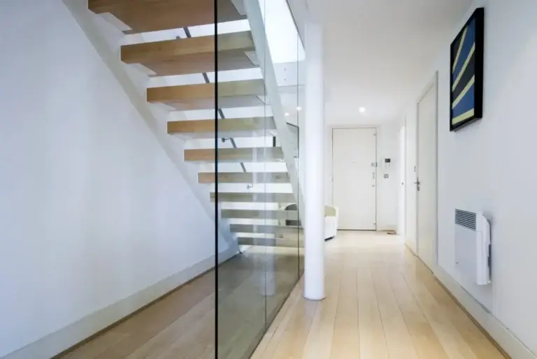Frameless glass panel beside an open staircase in a hallway