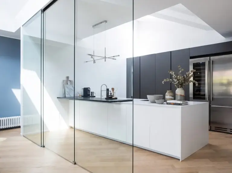 Frameless glass panels around a white kitchen