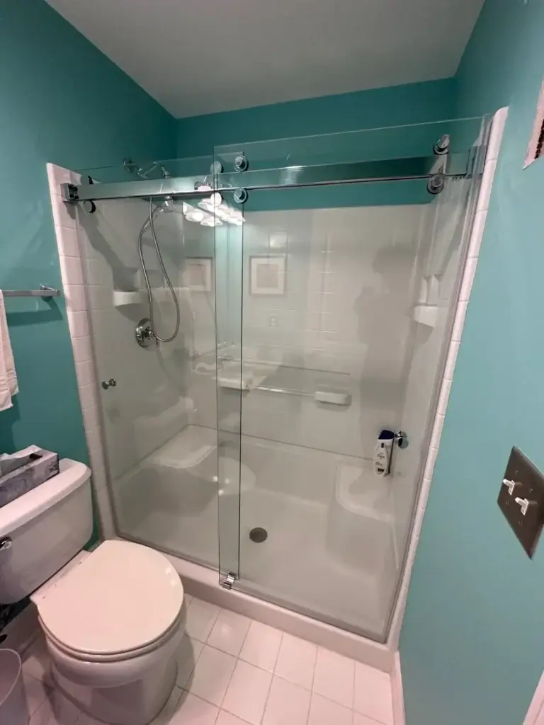 Frameless sliding shower door on a one-piece white shower surround