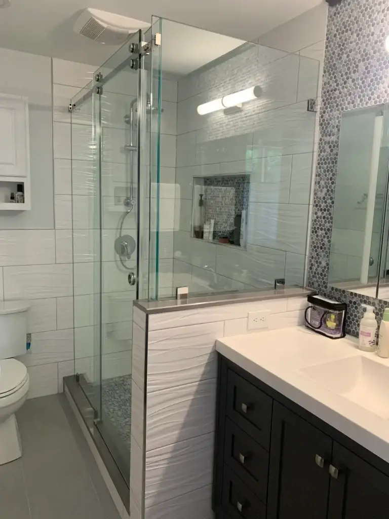 Side view of a frameless sliding shower enclosure on a tiled knee wall