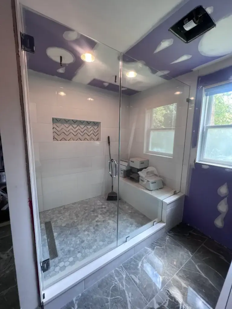 Frameless glass steam shower enclosure with a transom and bench