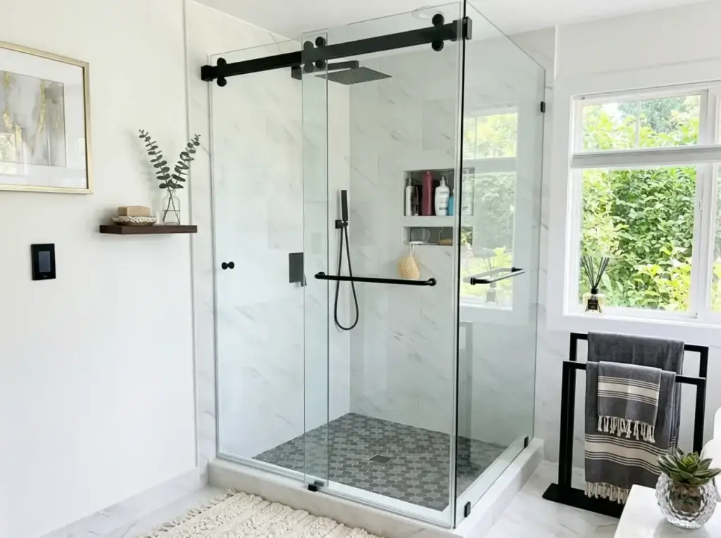 Sliding barn-style glass shower door on a black track over marble tile in a McLean, VA bathroom