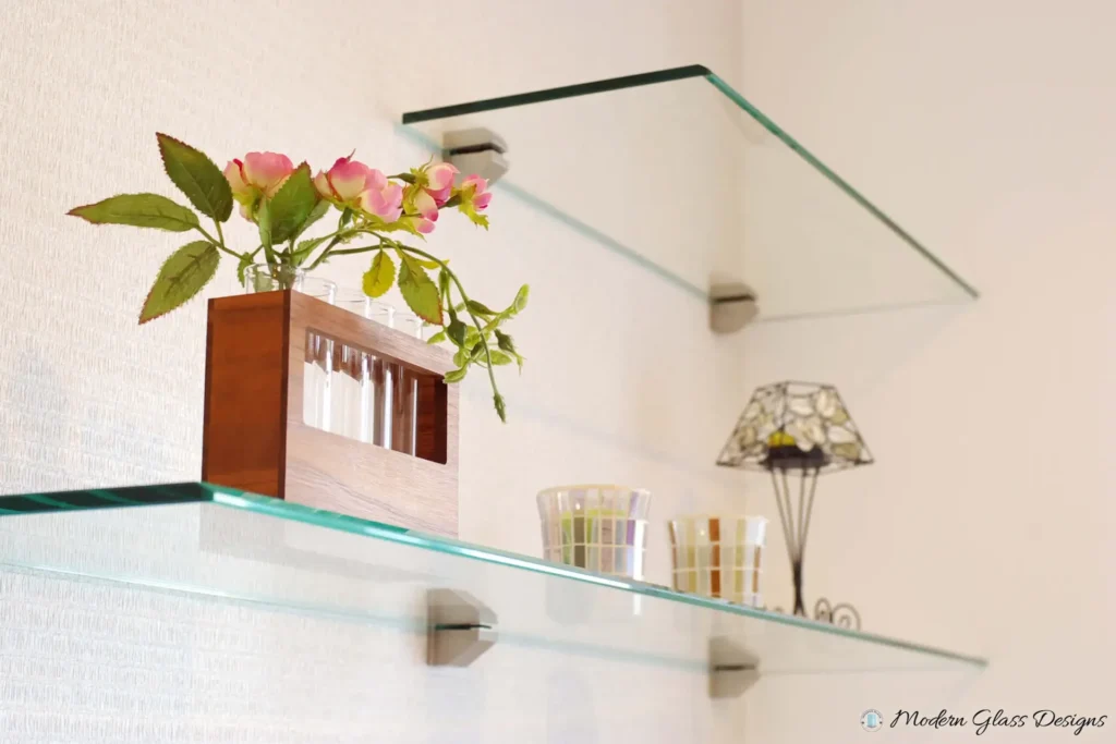 Floating glass shelves on metal brackets holding flowers and decor