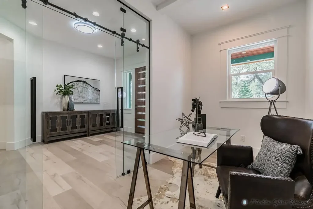 Frameless glass sliding door on a black barn-door track in a home office