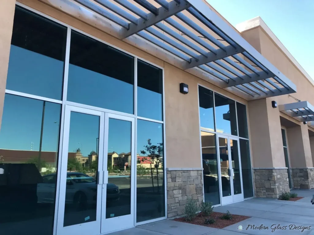 Tinted storefront glass in aluminum framing under a metal canopy