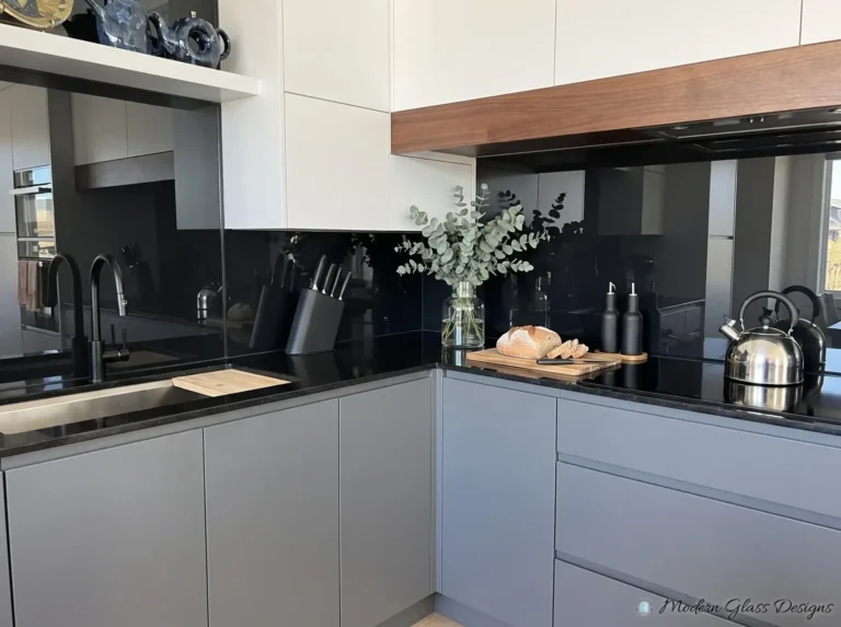 Black back-painted glass backsplash with gray lower cabinets and a black countertop