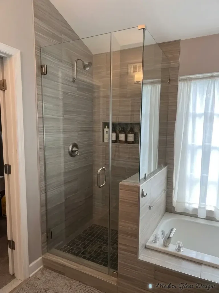 Frameless shower door and knee wall panel beside a soaking tub