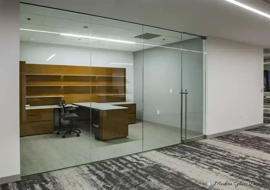 Frameless glass private office with a glass door and wood desk