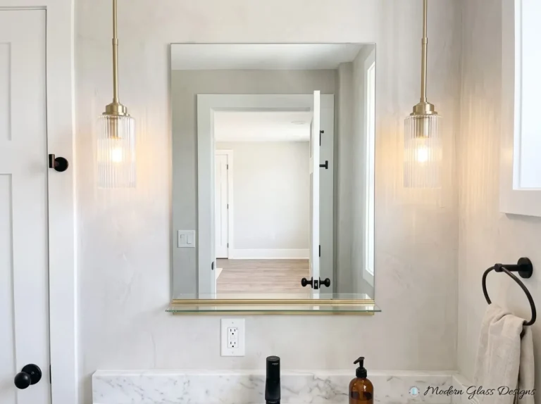Frameless mirror with a glass shelf below and brass pendant lights