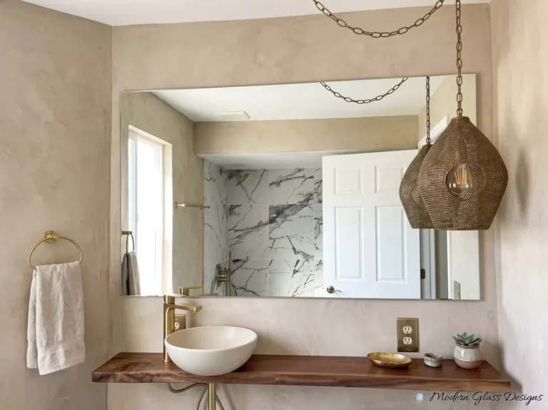 Frameless mirror above a wood shelf vanity with a vessel sink