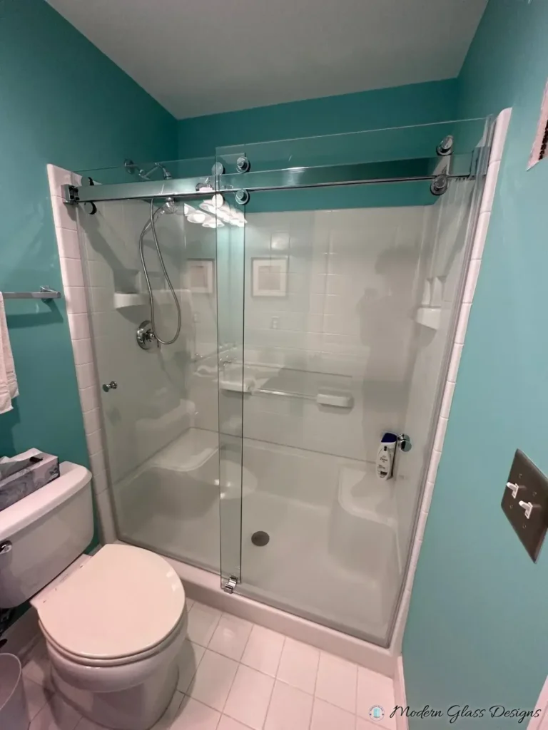 Frameless sliding shower door on a one-piece white shower surround