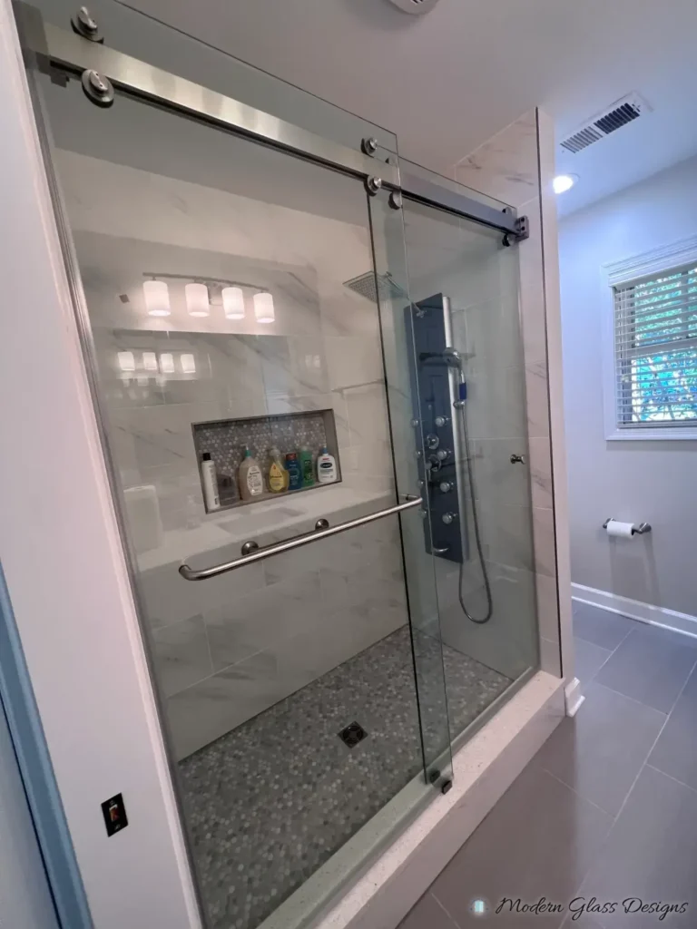 Frameless sliding shower door in a marble-look tile shower with a shower panel system