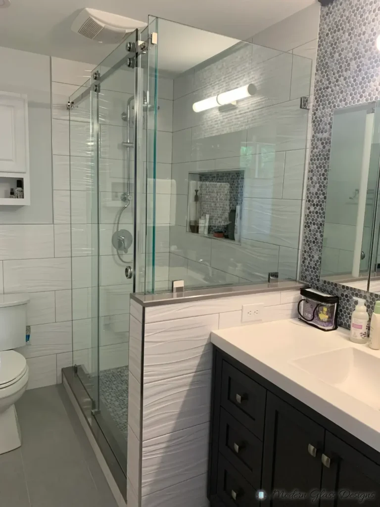 Side view of a frameless sliding shower enclosure on a tiled knee wall