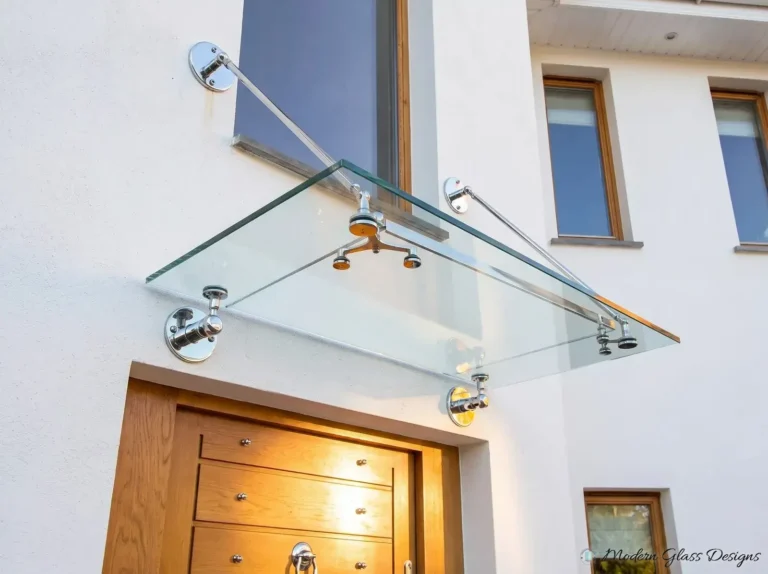 Clear glass canopy with polished chrome rods and point fittings above a wood front door