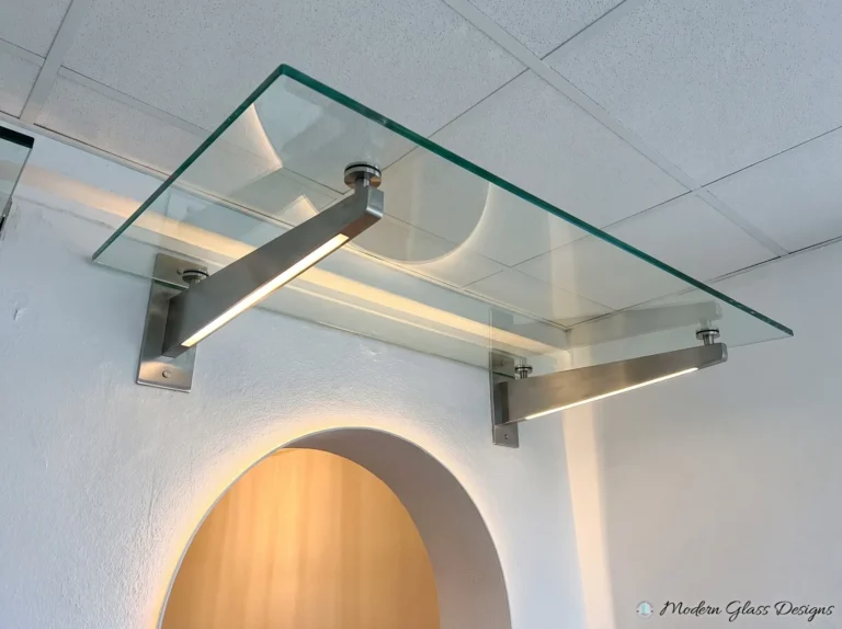Glass canopy on stainless arms with built-in lighting above an arched doorway