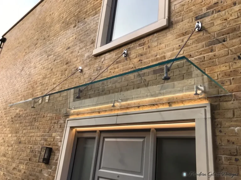 Clear glass canopy on three support rods above a front door on a brick wall