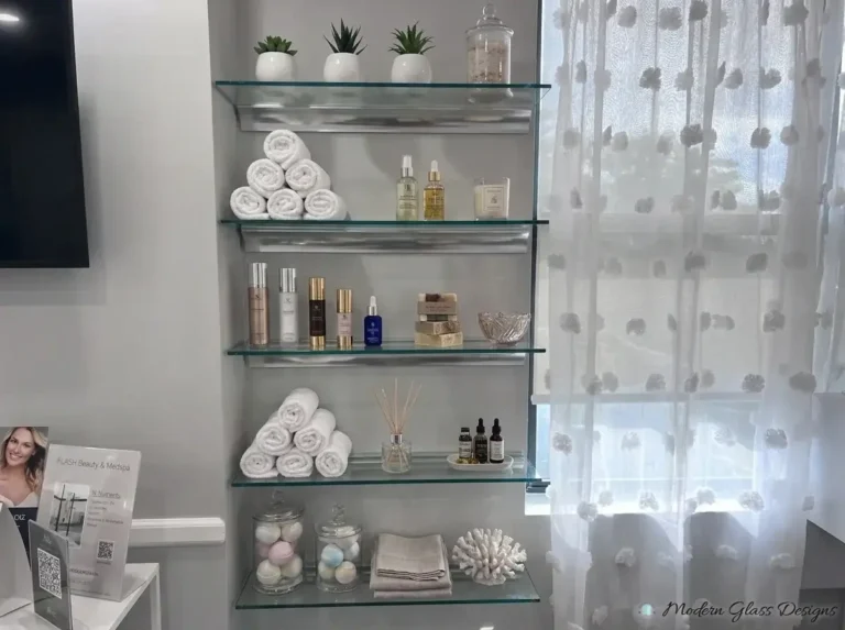 Glass shelves with towels and bottles beside a window