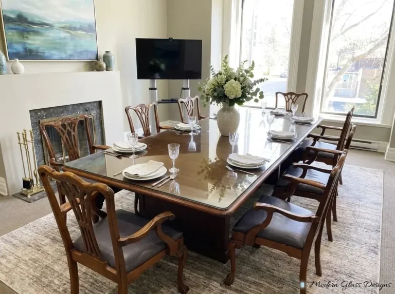 Glass top on a large wood table with upholstered chairs