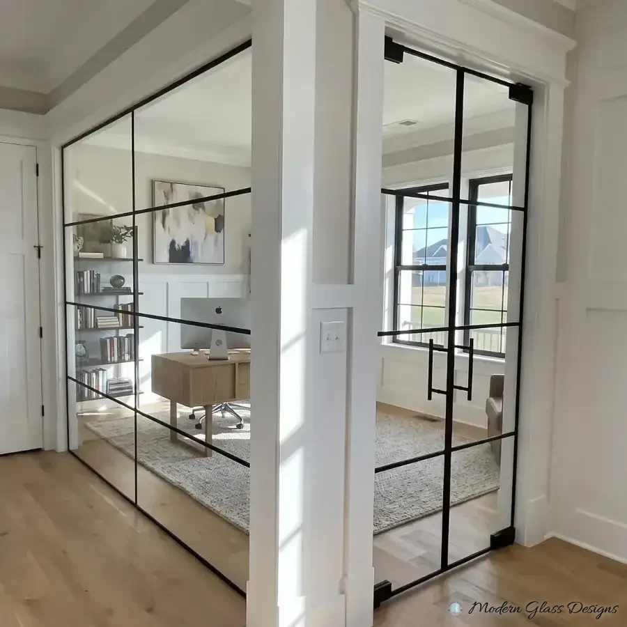 Black grid glass wall and double doors with ladder pulls enclosing a home office