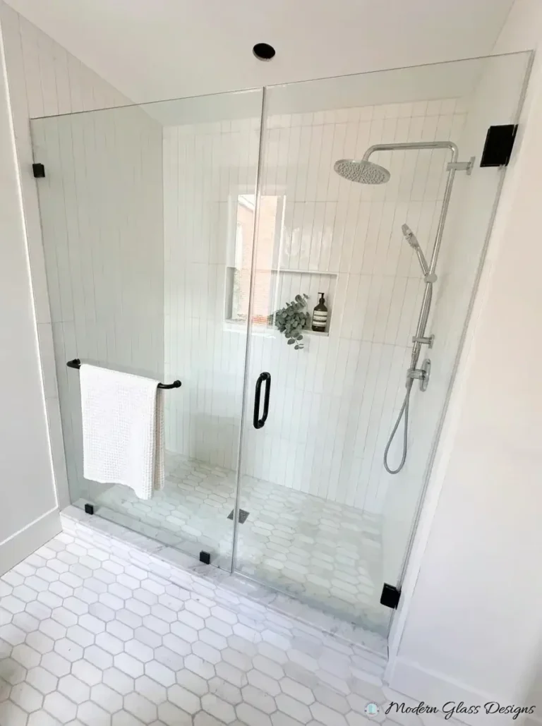 Frameless inline shower door and panel with matte black hinges and towel bar