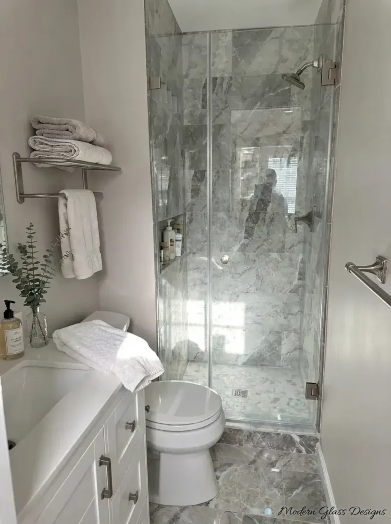 Narrow frameless inline shower door and panel in a gray marble tile shower