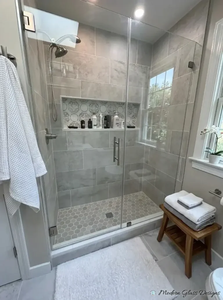 Frameless inline shower door and panel with brushed nickel hardware on gray tile