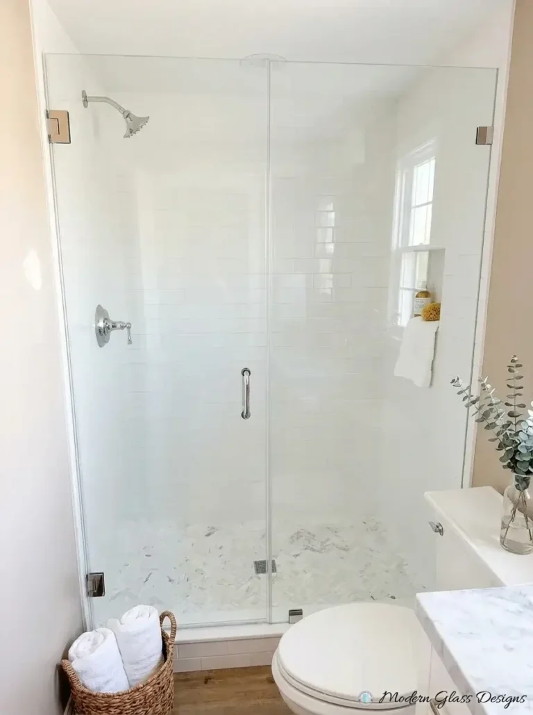 Frameless inline shower door and panel with brushed nickel hinges on subway tile