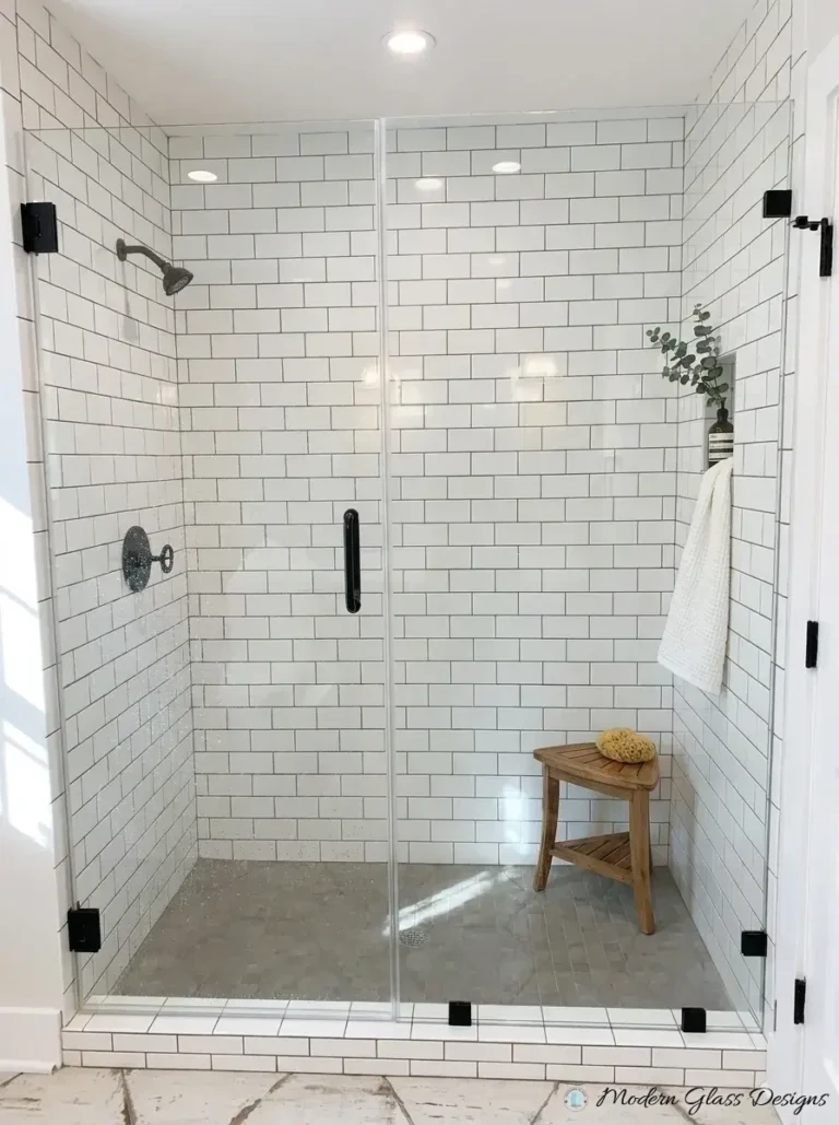 Frameless inline shower door and panel with matte black clamps on subway tile