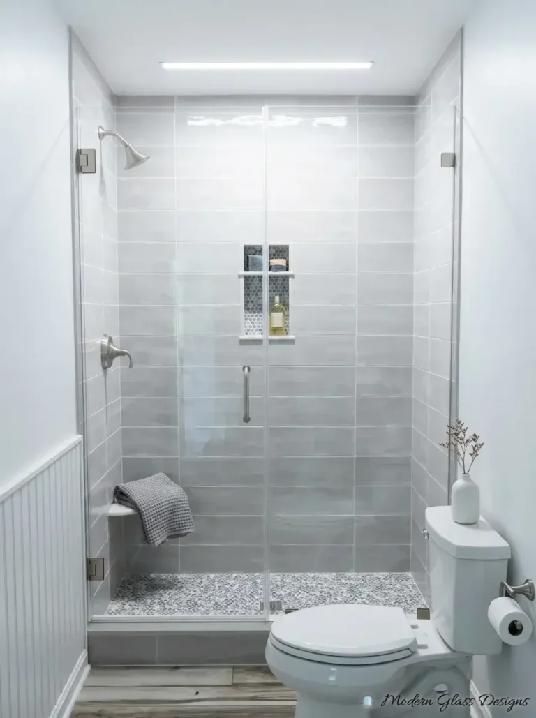 Frameless inline shower door and panel with brushed nickel hinges on gray tile