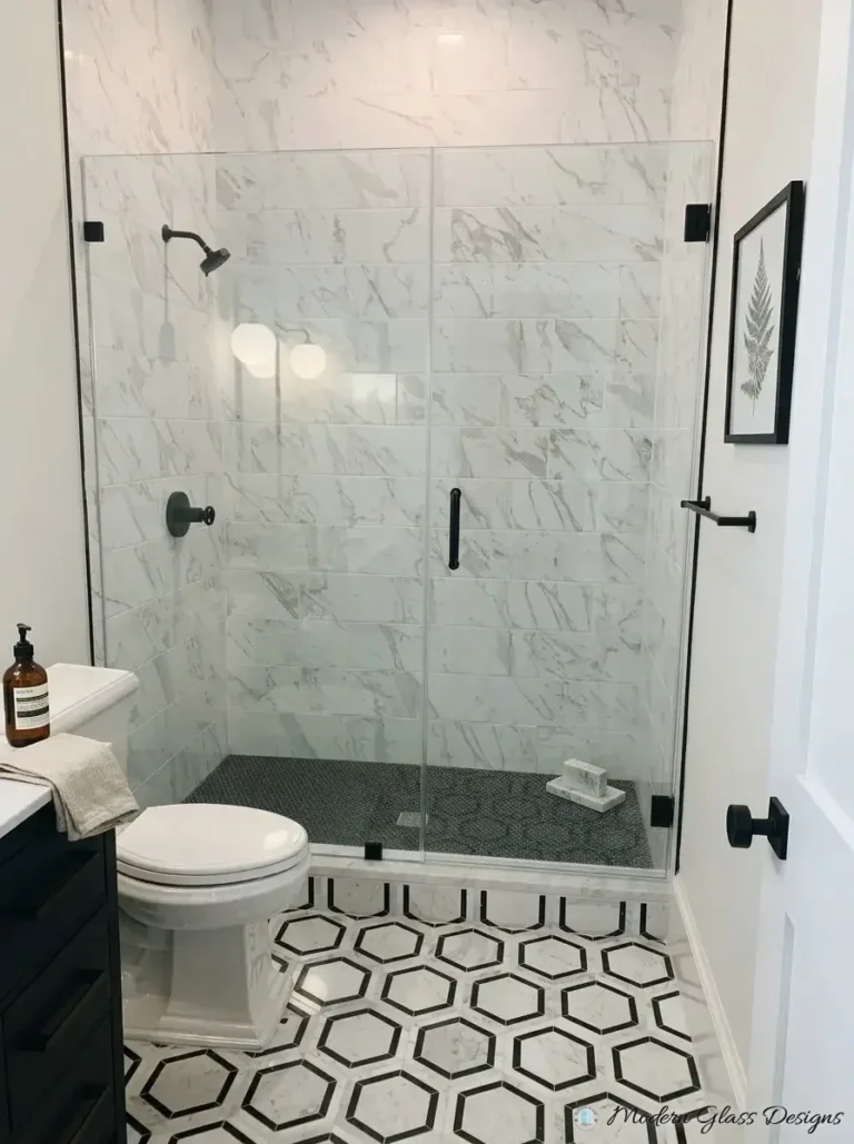 Frameless inline shower panel and door with matte black clamps on marble tile