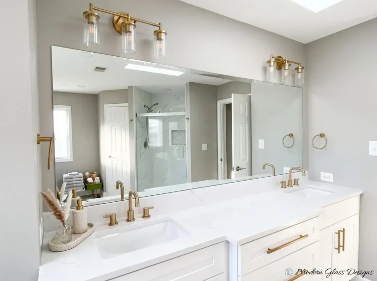 Long frameless mirror above a double vanity with a light fixture mounted on the mirror