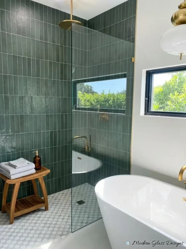 Fixed shower screen with brushed gold clamp on green tile