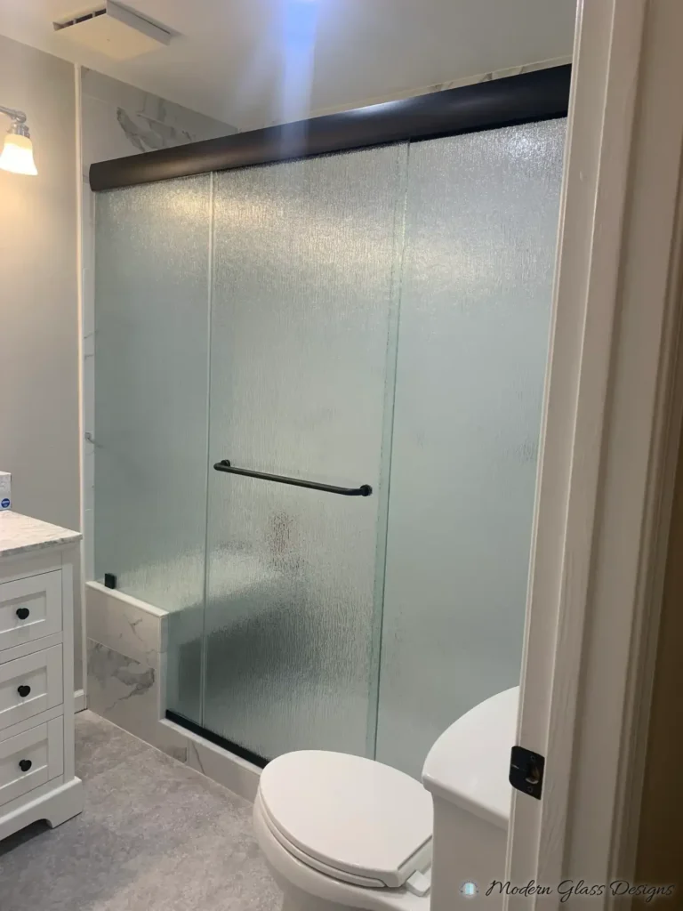 Sliding shower door with textured glass and a dark header rail