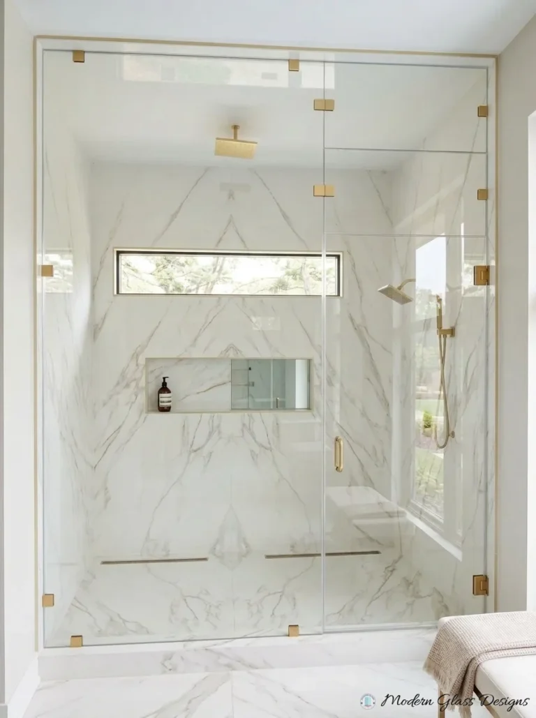 Floor-to-ceiling steam shower front with brushed brass clamps and transom